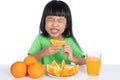 Asian Chinese little girl eating sour orange and making grimace Royalty Free Stock Photo