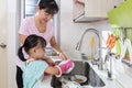 Asian Chinese little girl helping mother washing dishes Royalty Free Stock Photo