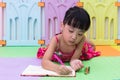 Asian Chinese little girl laying on the floor coloring Royalty Free Stock Photo