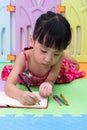 Asian Chinese little girl laying on the floor coloring Royalty Free Stock Photo