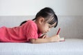 Asian Chinese little girl laying on the sofa writing book Royalty Free Stock Photo