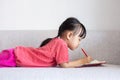 Asian Chinese little girl laying on the sofa writing book Royalty Free Stock Photo