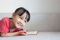 Asian Chinese little girl laying on the sofa writing book Royalty Free Stock Photo