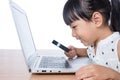 Asian Chinese little girl looking at laptop through magnifier