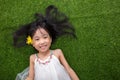 Asian Chinese little girl lying on the grass with flower Royalty Free Stock Photo