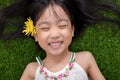 Asian Chinese little girl lying on the grass with flower Royalty Free Stock Photo