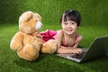 Asian Chinese little girl playing laptop with teddy bear Royalty Free Stock Photo