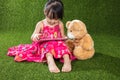 Asian Chinese little girl playing tablet computer with teddy bear