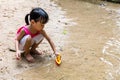 Asian Chinese little girl playing toy boat at creek