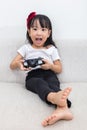 Asian Chinese little girl playing TV games on the sofa