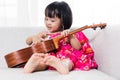 Asian Chinese little girl playing ukele Royalty Free Stock Photo