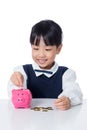 Asian Chinese little girl putting coins into piggy bank Royalty Free Stock Photo