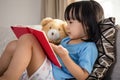 Asian Chinese little girl reading book with teddy bear Royalty Free Stock Photo