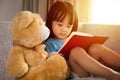 Asian Chinese little girl reading book with teddy bear Royalty Free Stock Photo