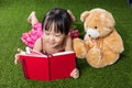 Asian Chinese little girl reading book with teddy bear Royalty Free Stock Photo