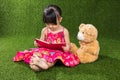 Asian Chinese little girl reading book with teddy bear Royalty Free Stock Photo