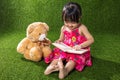 Asian Chinese little girl reading book with teddy bear Royalty Free Stock Photo