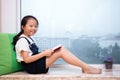 Asian Chinese little girl reading book on the windowsill