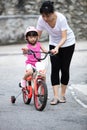 Asian Chinese little girl riding bicycle with mom guide Royalty Free Stock Photo