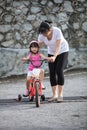 Asian Chinese little girl riding bicycle with mom guide Royalty Free Stock Photo