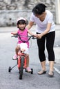 Asian Chinese little girl riding bicycle with mom guide Royalty Free Stock Photo