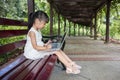 Asian Chinese little girl sitting on the bench with laptop Royalty Free Stock Photo