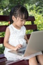 Asian Chinese little girl sitting on the bench with laptop Royalty Free Stock Photo