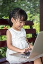 Asian Chinese little girl sitting on the bench with laptop Royalty Free Stock Photo