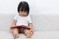 Asian Chinese little girl sitting on the sofa with book Royalty Free Stock Photo