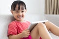 Asian Chinese little girl sitting on the sofa playing digital ta Royalty Free Stock Photo