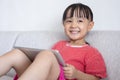 Asian Chinese little girl sitting on the sofa playing digital ta Royalty Free Stock Photo