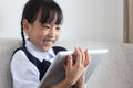 Asian Chinese little girl sitting on the sofa playing digital ta Royalty Free Stock Photo