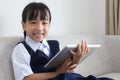 Asian Chinese little girl sitting on the sofa playing digital ta Royalty Free Stock Photo