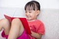 Asian Chinese little girl sitting on the sofa reading book Royalty Free Stock Photo