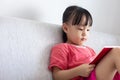 Asian Chinese little girl sitting on the sofa reading book Royalty Free Stock Photo