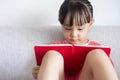 Asian Chinese little girl sitting on the sofa reading book Royalty Free Stock Photo