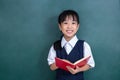Asian Chinese little Girl in uniform reading book against green