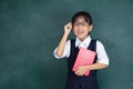 Asian Chinese little Girl in uniform standing against green blackboard