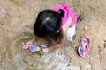 Asian Chinese little girl washing sandals at riverbank Royalty Free Stock Photo