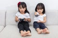 Asian Chinese little sisters playing TV games on the sofa Royalty Free Stock Photo