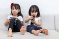 Asian Chinese little sisters playing TV games on the sofa Royalty Free Stock Photo