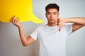 Asian chinese man holding speech bubble standing over isolated white background with angry face, negative sign showing dislike Royalty Free Stock Photo