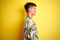 Asian chinese man on holiday wearing summer shirt over isolated yellow background looking to side, relax profile pose with natural Royalty Free Stock Photo