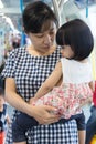 Asian Chinese mother carrying daughter inside a MRT transit Royalty Free Stock Photo