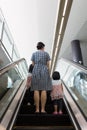 Asian Chinese mother and daughters taking escalator at MRT Station