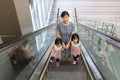 Asian Chinese mother and daughters taking escalator at MRT Station