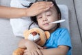 Asian Chinese mother measuring little girl forehead for fever