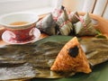 Asian Chinese rice dumplings. Zongzi is placed on the green plate on the leaf, on the wooden tray, there is a cup of chi Royalty Free Stock Photo