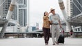 Asian chinese senior tourist couple with black luggage walking together in city with map on hand during having city sightseeing Royalty Free Stock Photo