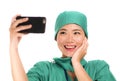 Asian Chinese woman as successful taking selfie on hand phone - young beautiful and happy medicine doctor or hospital nurse taking Royalty Free Stock Photo